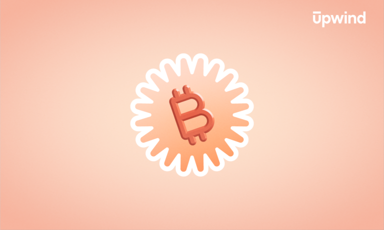A stylized bitcoin symbol sits in the center of a sunburst design with a peach background, hinting at the mysterious world of digital currencies and posing the question, What is Cryptojacking? The symbol is surrounded by wavy, white lines. The word upwind is in the top right corner.